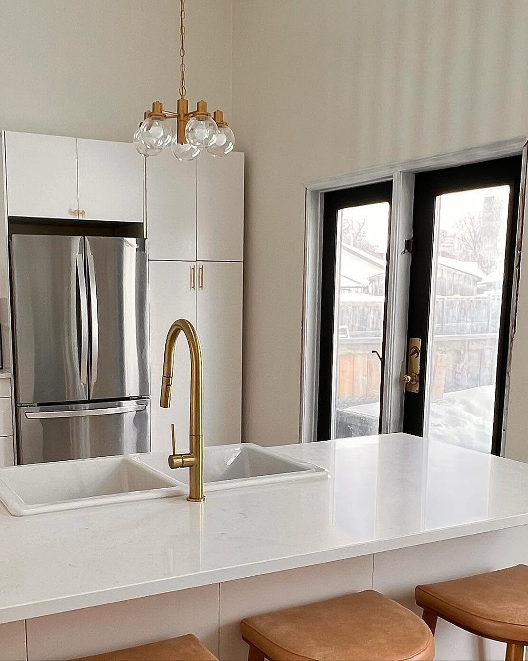 White kitchen island with a double sink and gold faucet in a modern kitchen