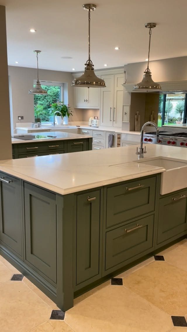 Green kitchen island with white countertop and a white farmhouse apron sink.