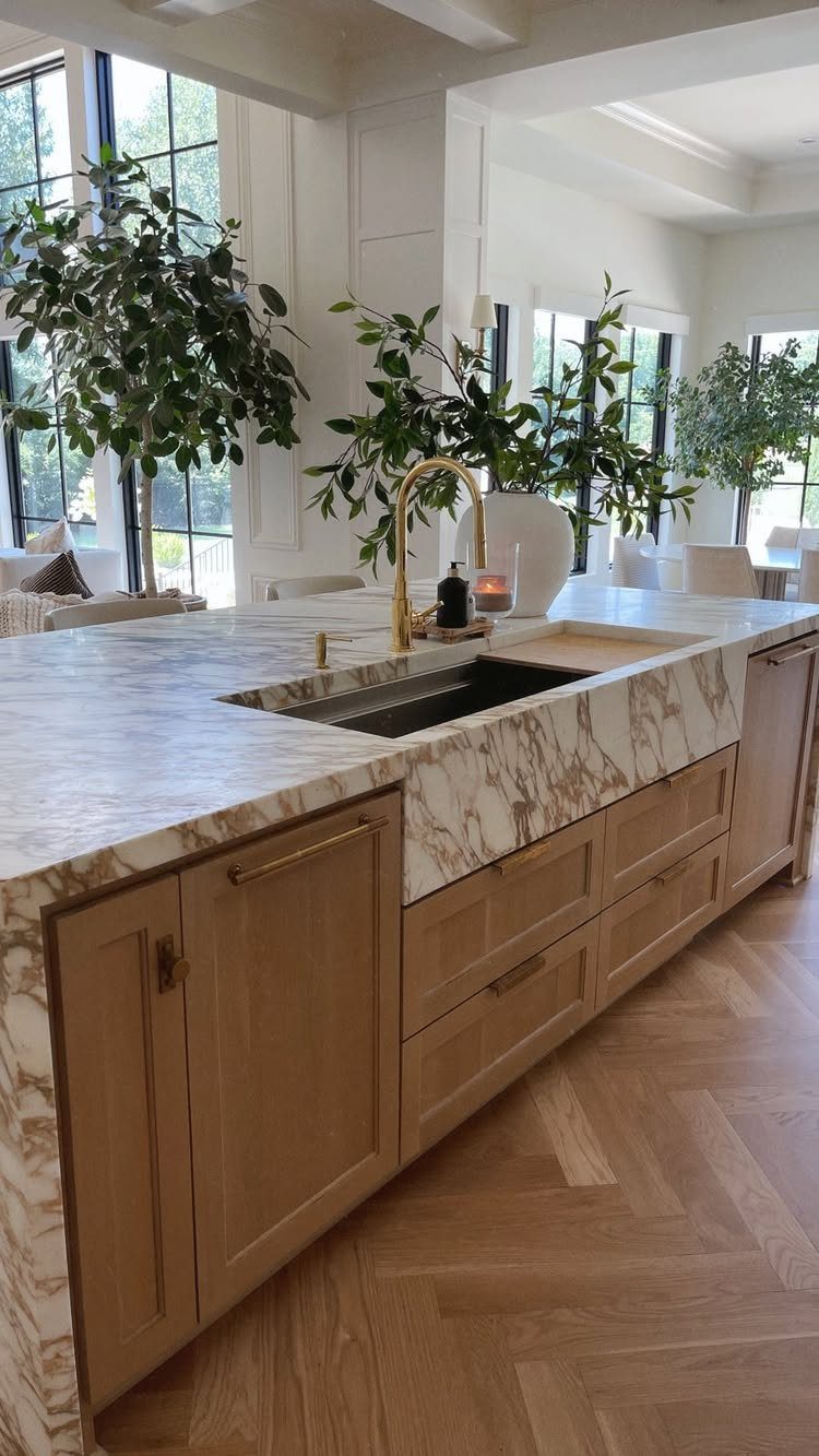 Kitchen island with white marble countertop, built-in sink, and light wood cabinets.