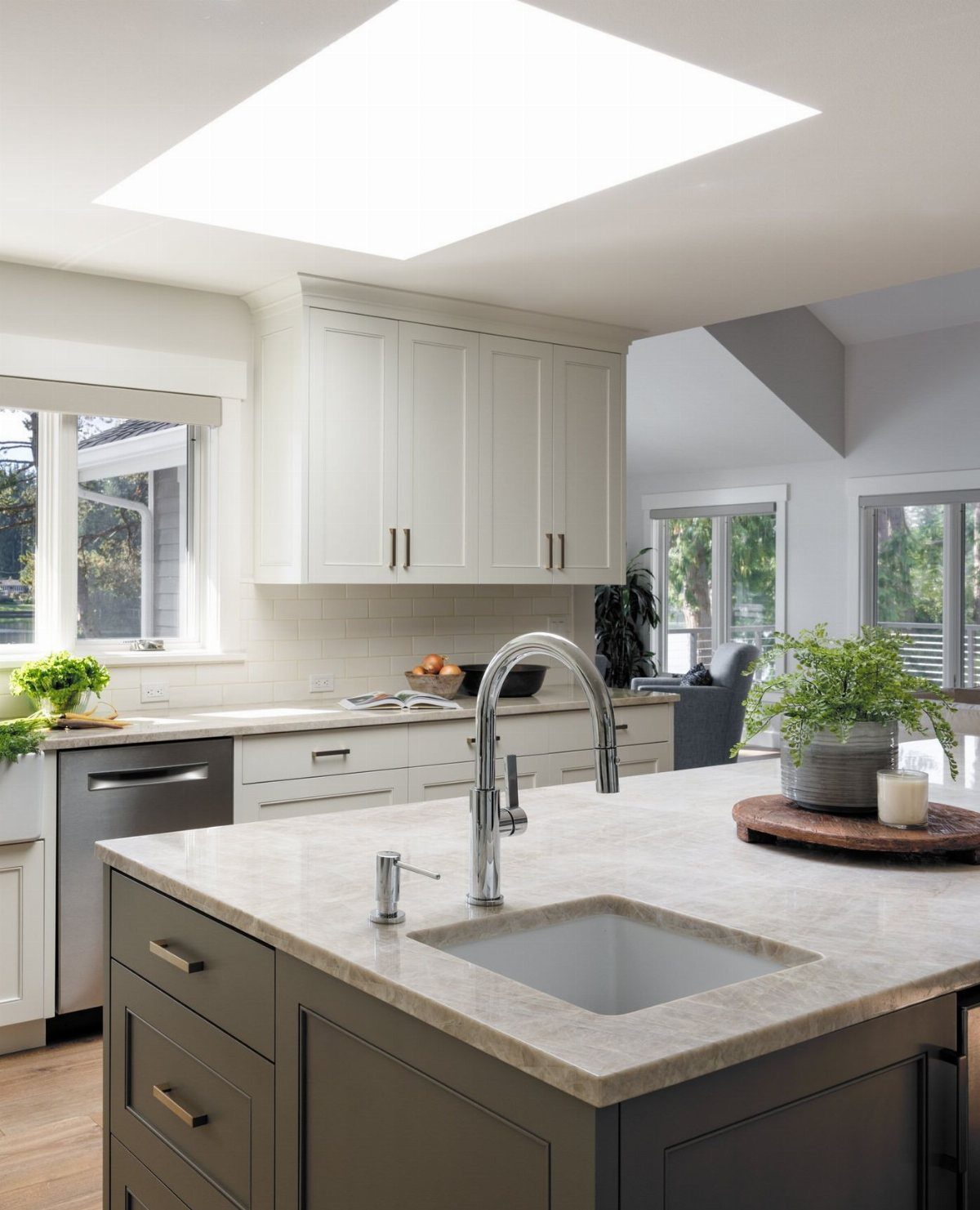 Small square sink in a dark grey kitchen island with white marble countertops.