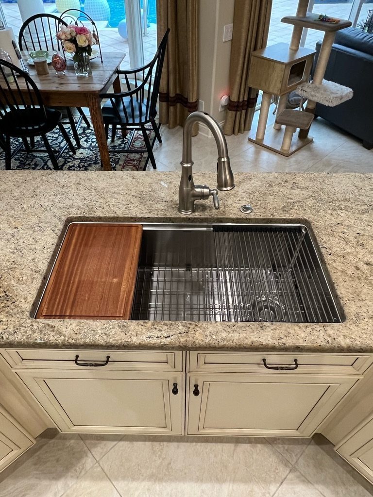 Kitchen island with a stainless steel sink and granite countertop in a home.