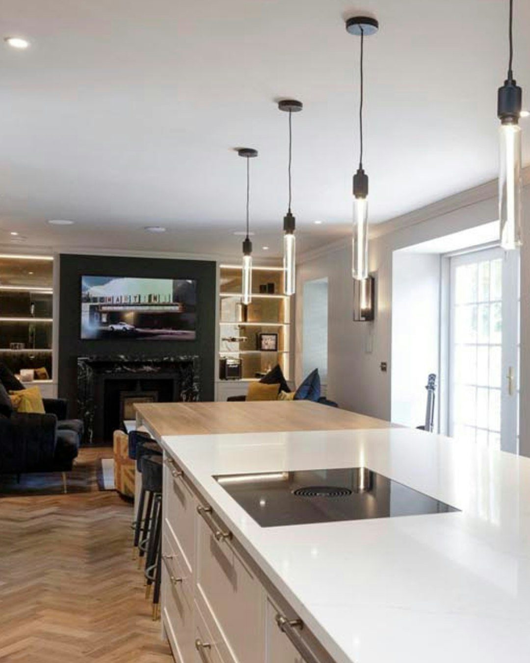White kitchen island with built-in black stovetop and wooden butcher block countertop.