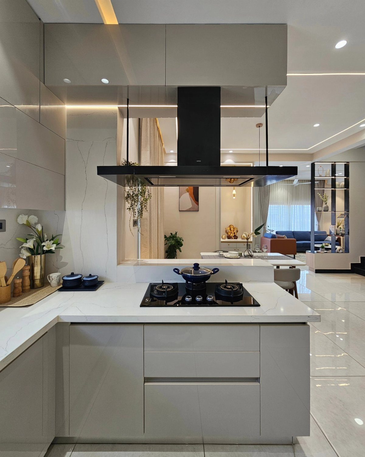 Modern kitchen island with white countertop, black gas stove, and overhead range hood.
