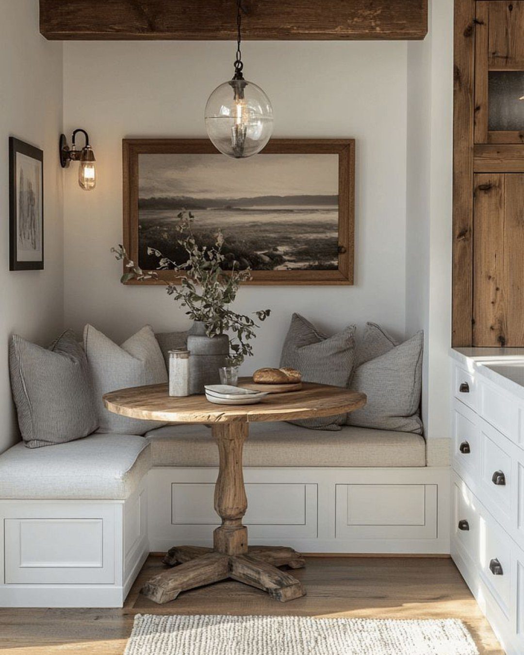Round wooden table and white built-in bench seating in a cozy dining nook.