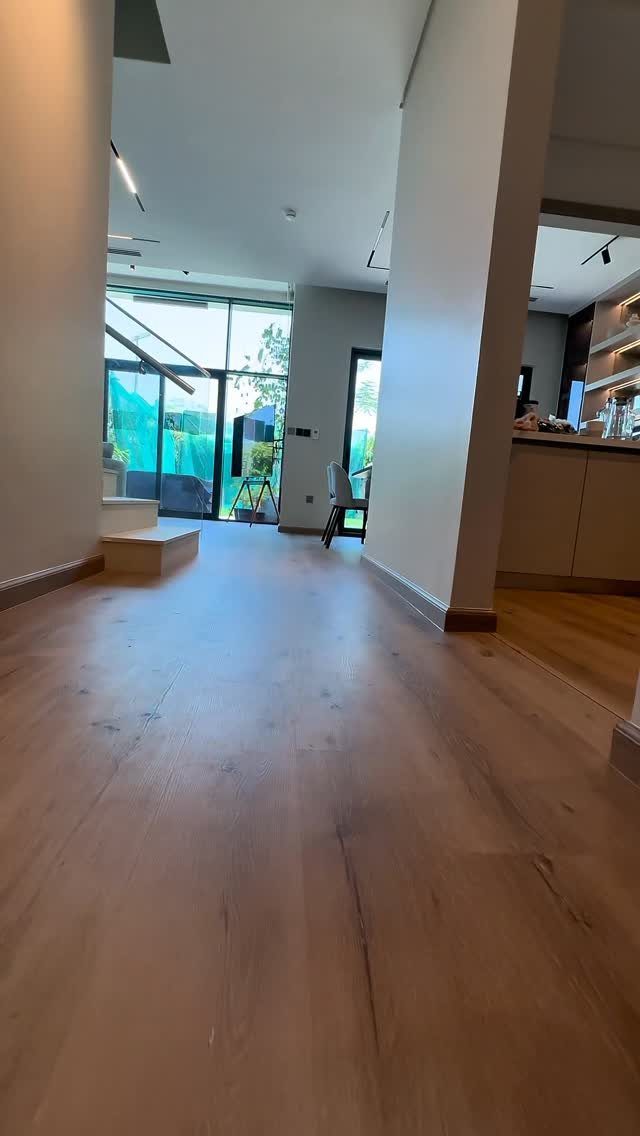 Light wood plank flooring extending through an open concept kitchen and living area.