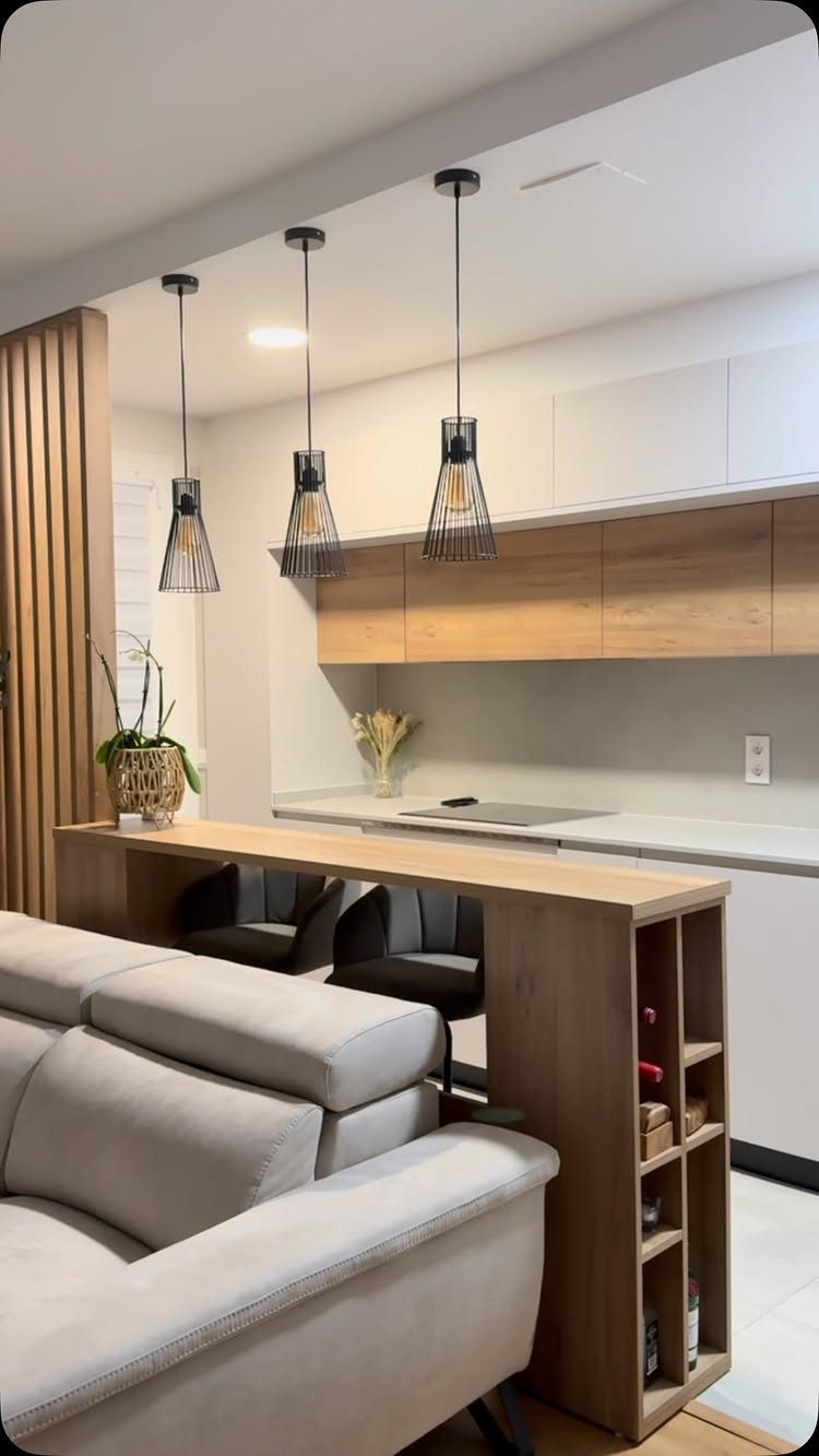 Three black geometric pendant lights hanging over a wooden kitchen breakfast bar
