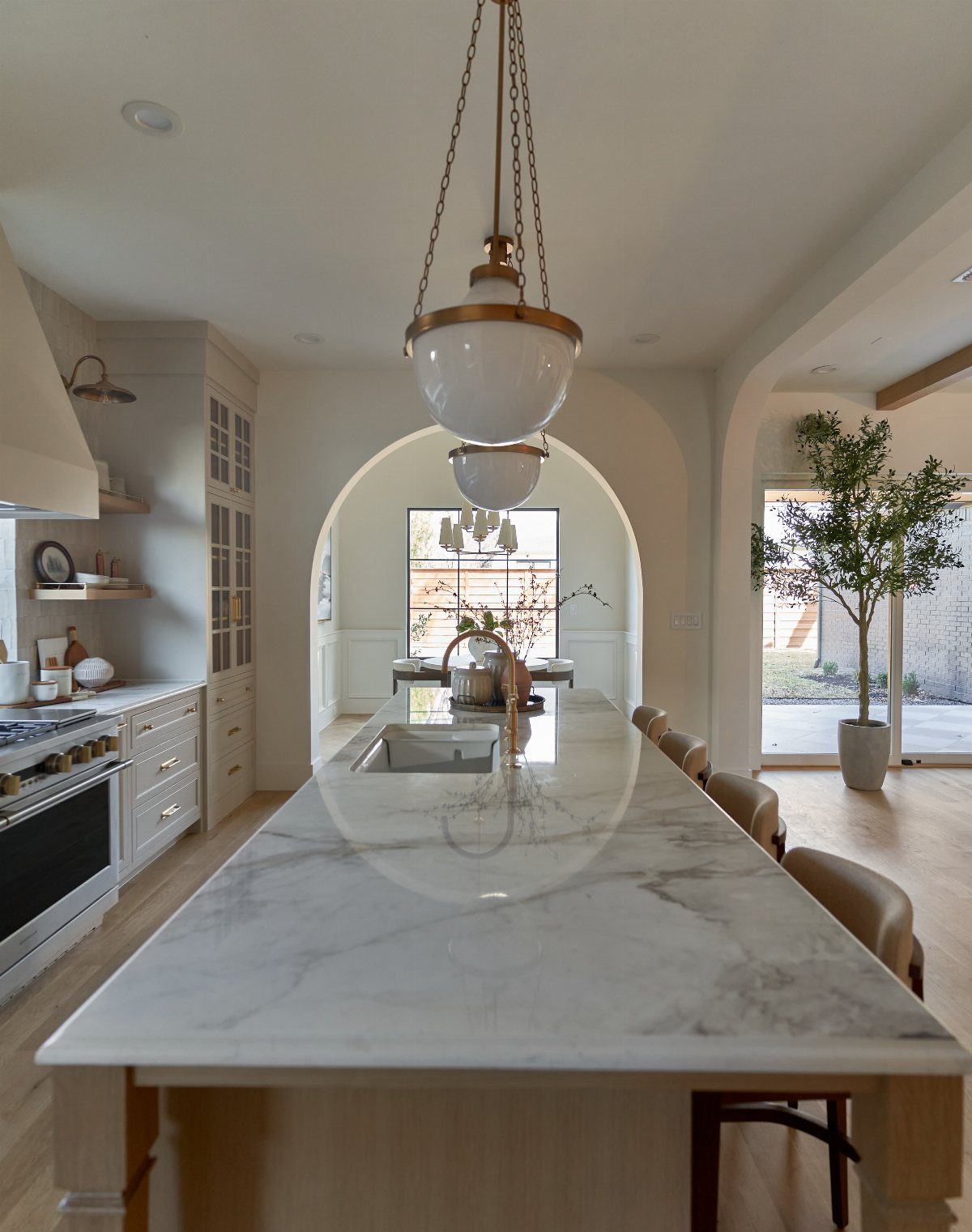 White marble kitchen island leading into an open living area with arched doorways.