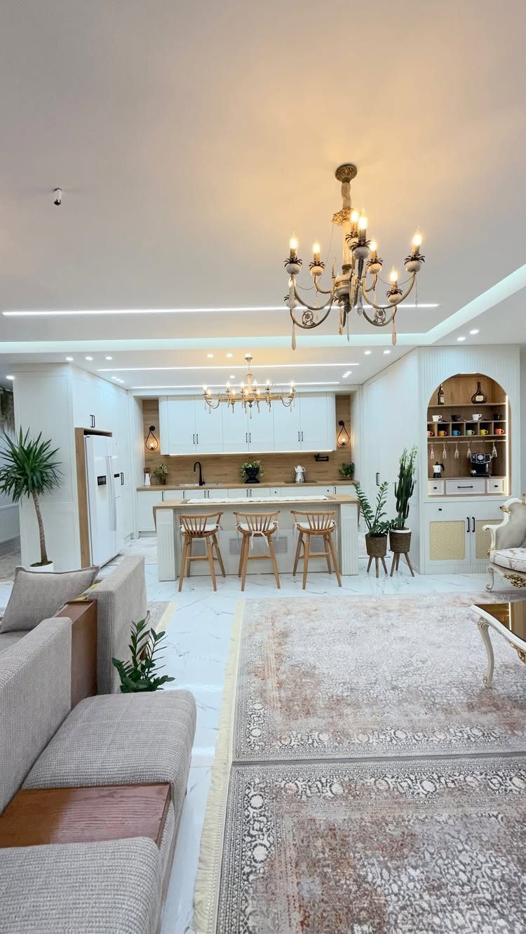 Open concept living room and kitchen with white cabinets and a large rug.