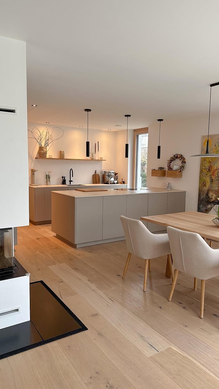 Modern open concept kitchen and dining area with neutral tones and light wood flooring.