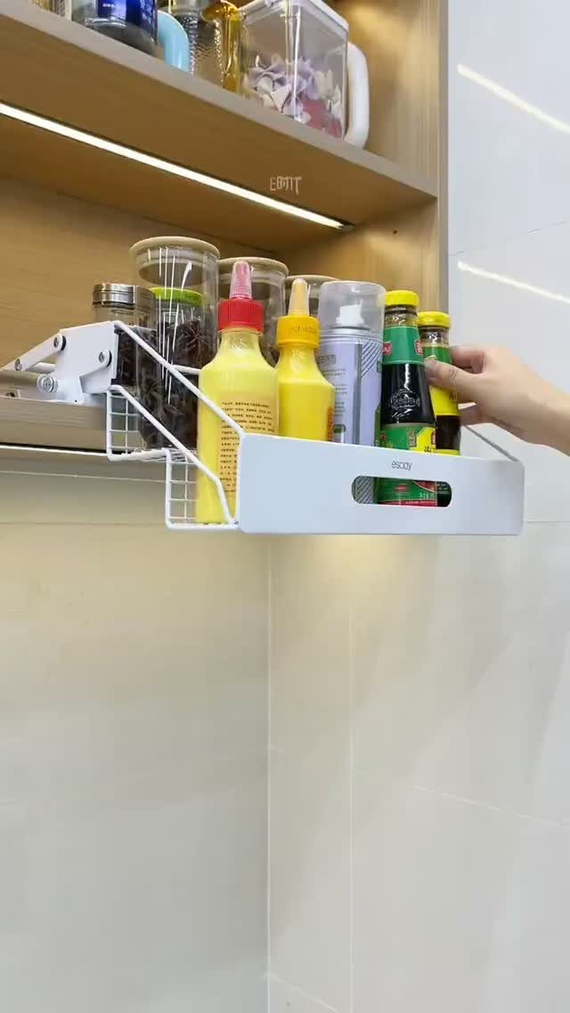 White pull-out under-shelf storage drawer holding condiment bottles in a modern kitchen.