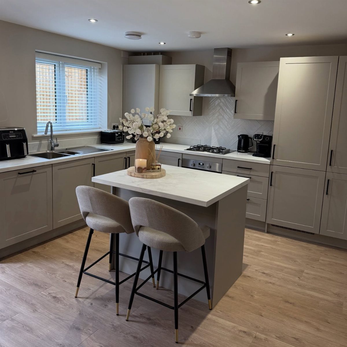 White kitchen island with two grey bar stools in a modern grey kitchen
