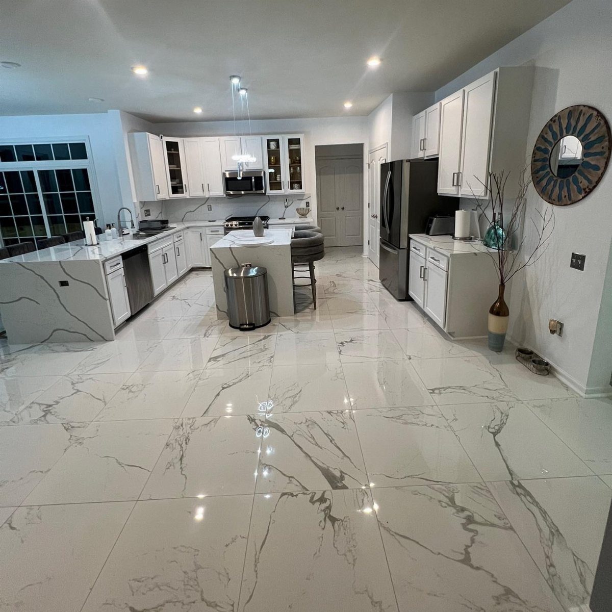 Modern white kitchen with white marble-patterned tile flooring and matching white cabinetry.