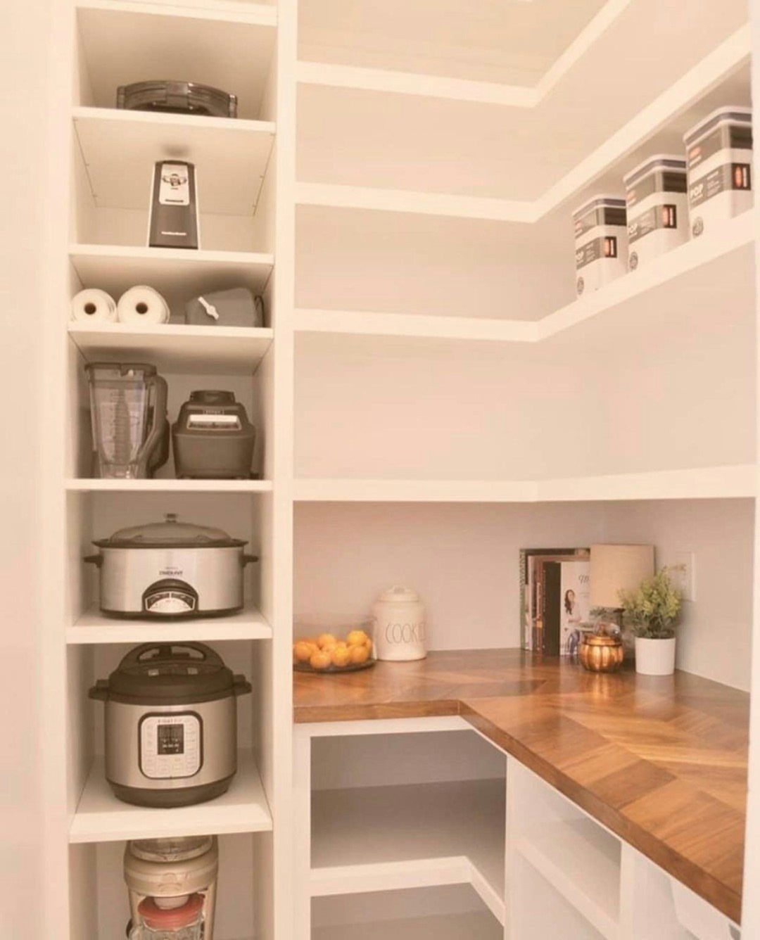 White built-in pantry shelves with kitchen appliances and a wooden butcher block counter.
