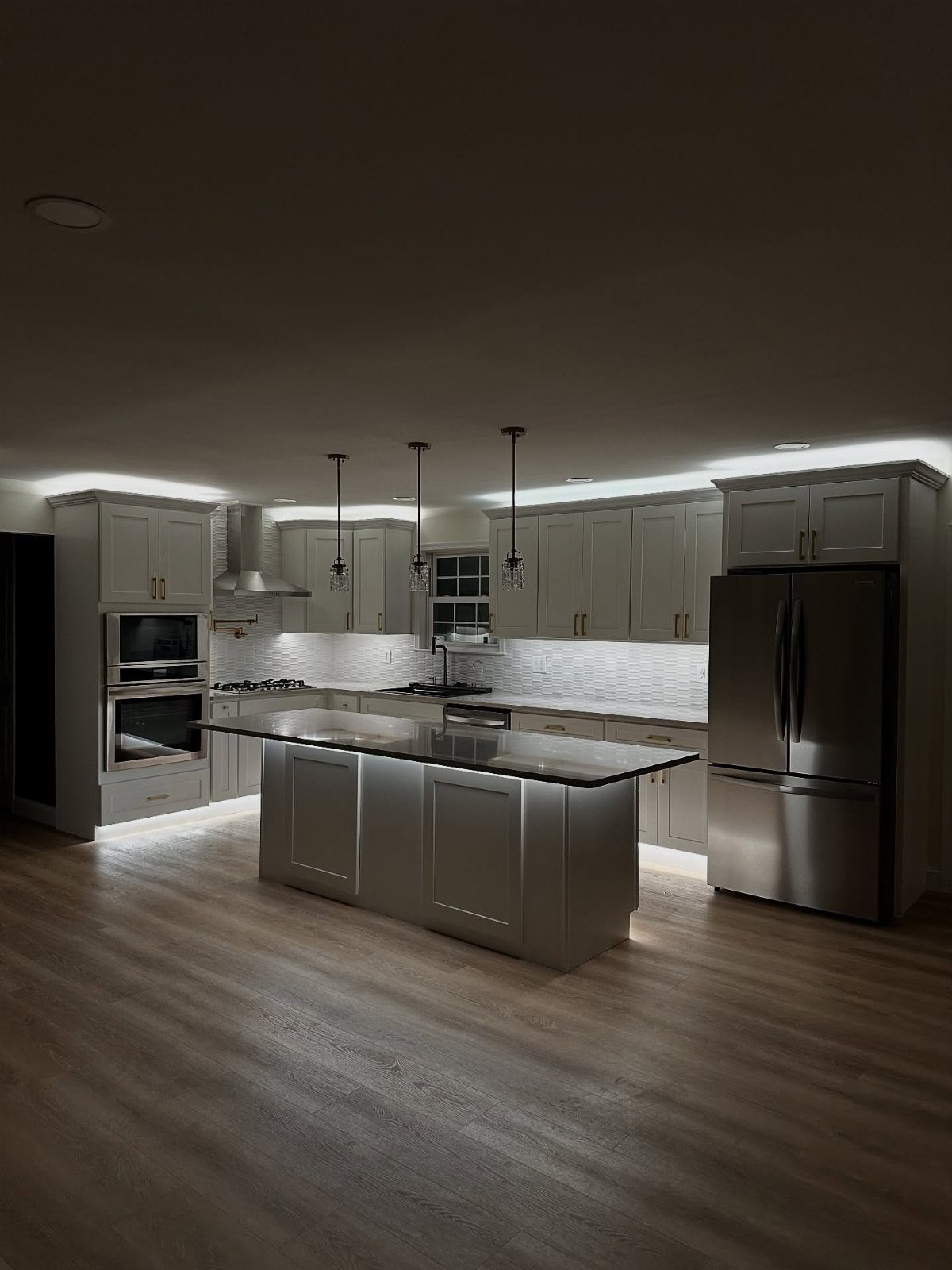 Modern kitchen featuring bright under-cabinet LED lighting and a central grey island.
