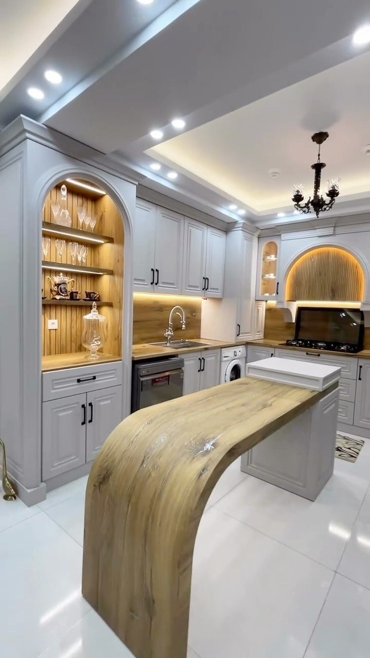 Modern kitchen with light grey cabinets and a curved wooden breakfast bar island.