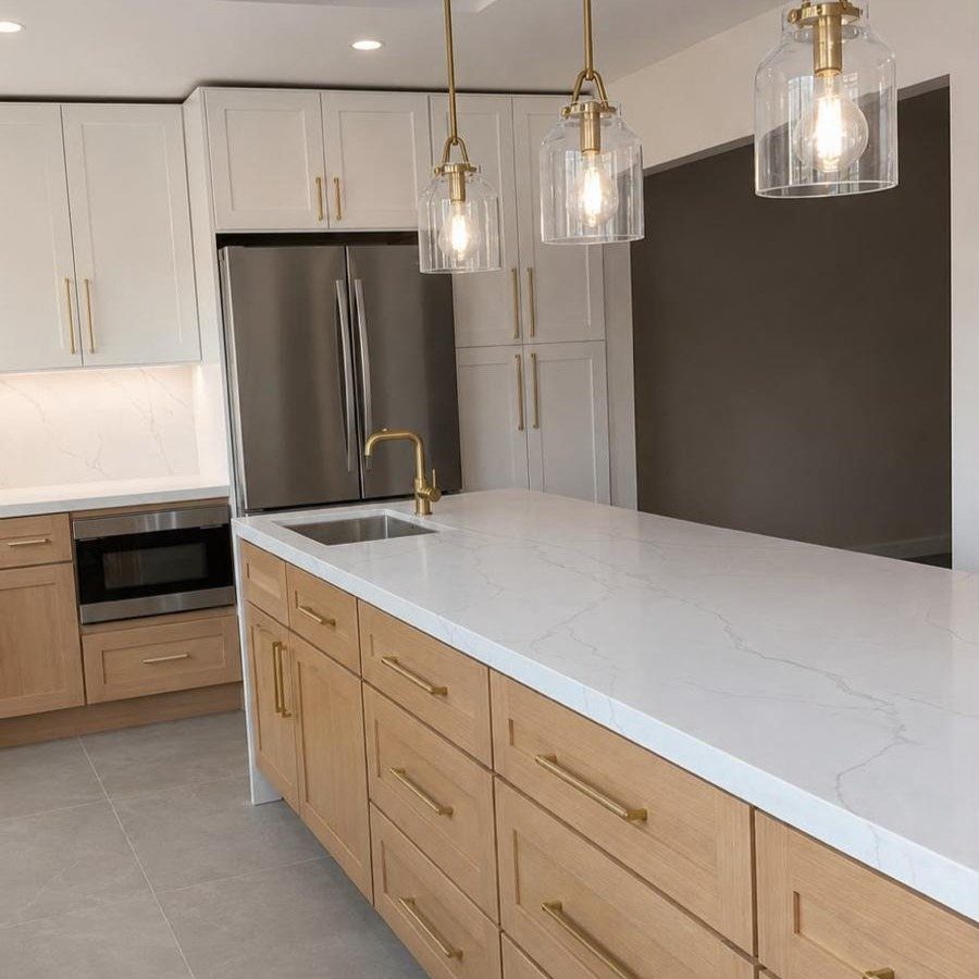 Modern kitchen with white upper cabinets, light wood lower cabinets, and white marble countertops.