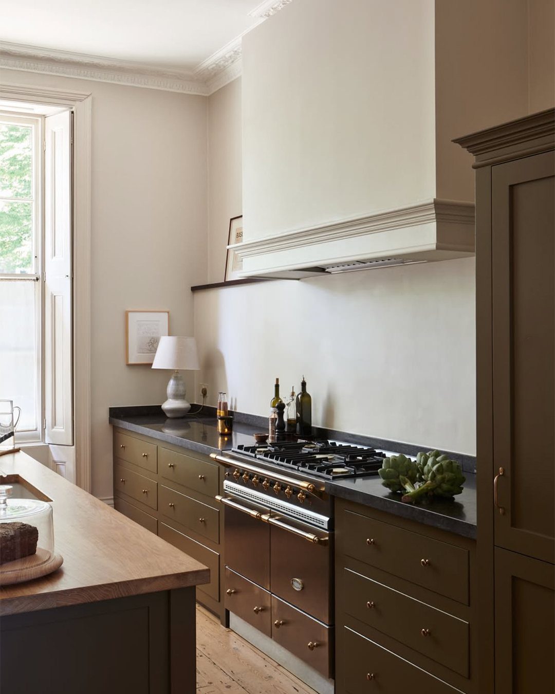Olive green kitchen cabinets with a dark countertop and a natural wood island surface.
