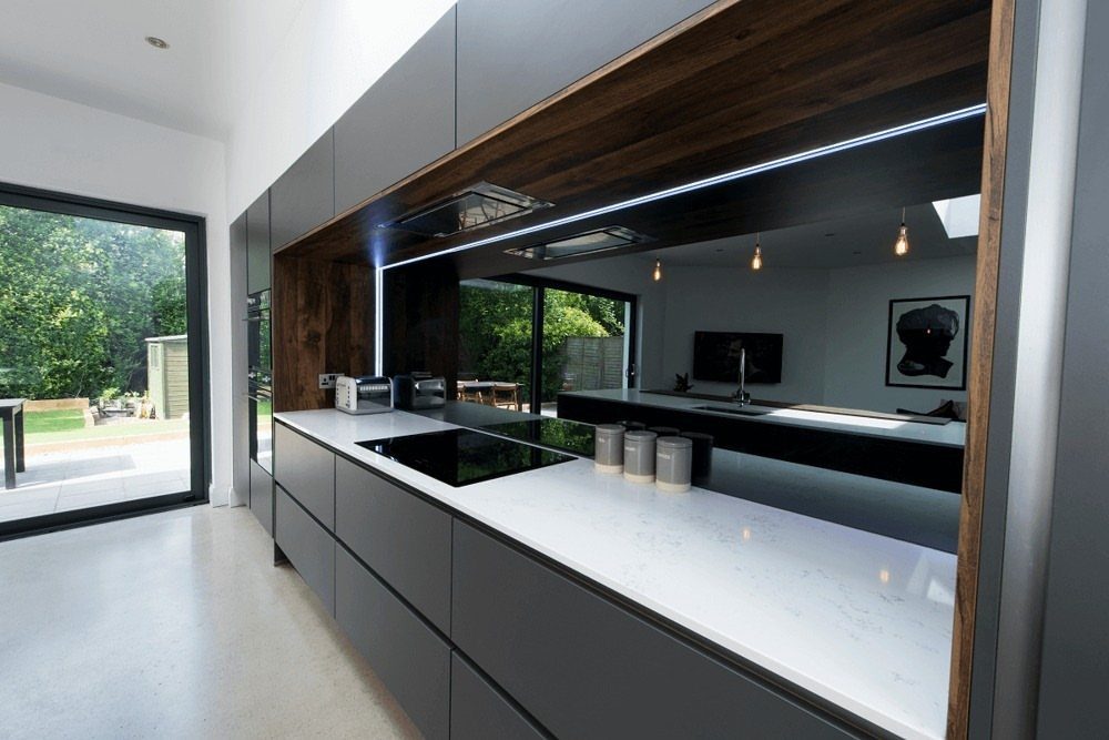 Modern kitchen with a black reflective glass backsplash and white countertops.
