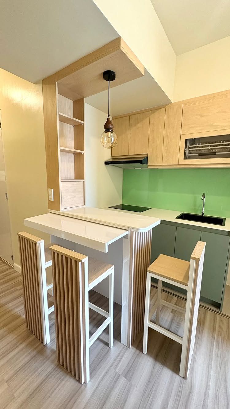 White breakfast bar with wooden slatted stools in a small modern kitchen.