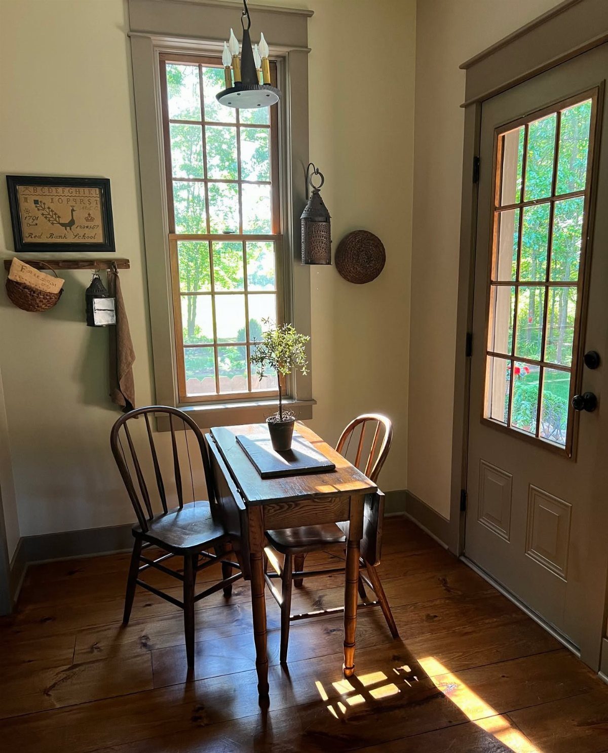 Small wooden rectangular table and two chairs in a sunlit kitchen nook.