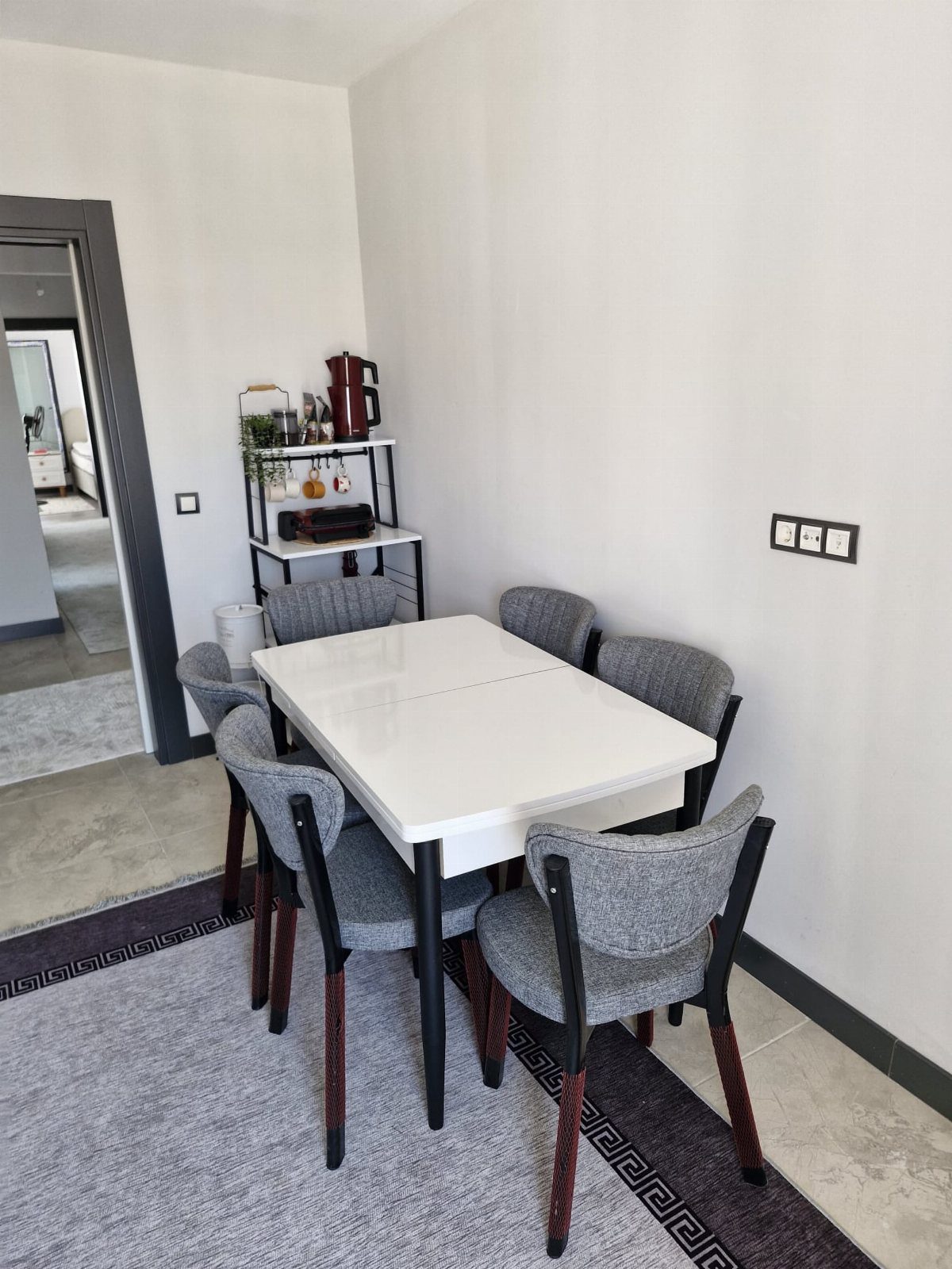 White kitchen table and grey chairs on a grey rug with purple border