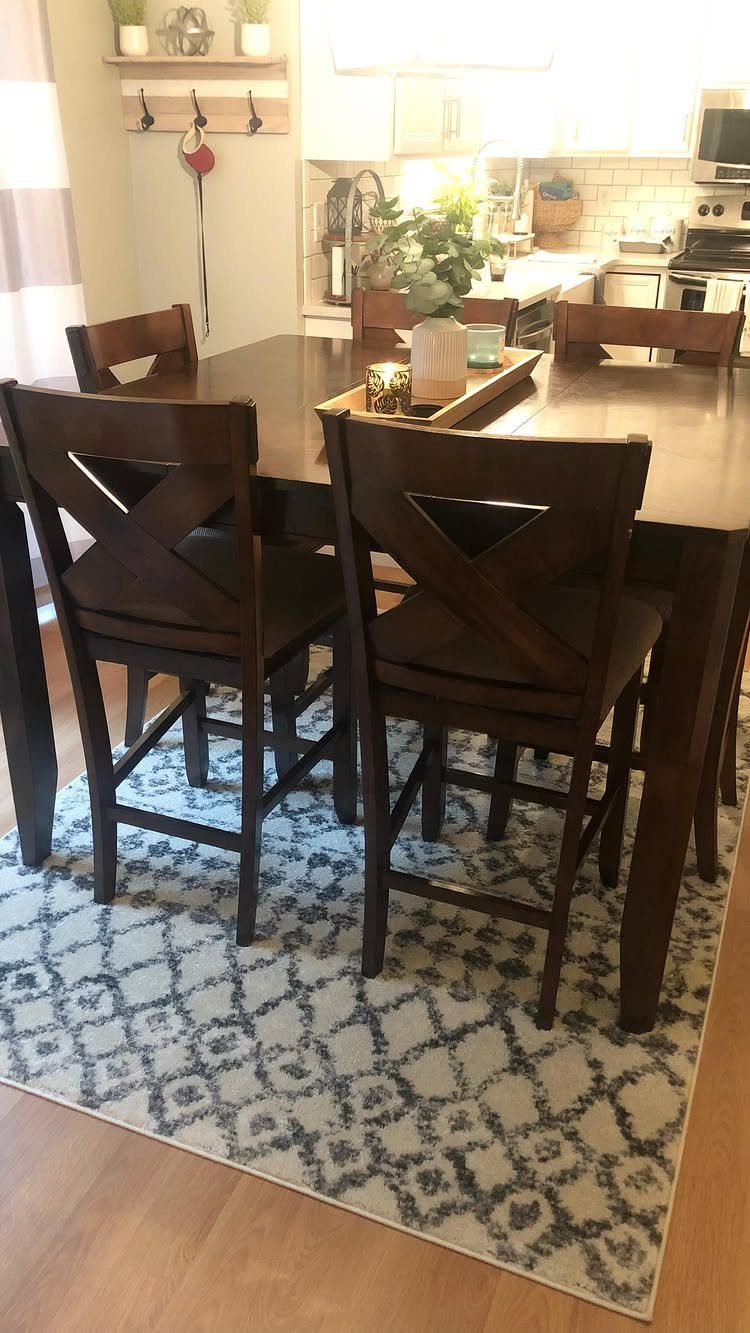 Dark wood kitchen table and chairs on a blue and white patterned rug.