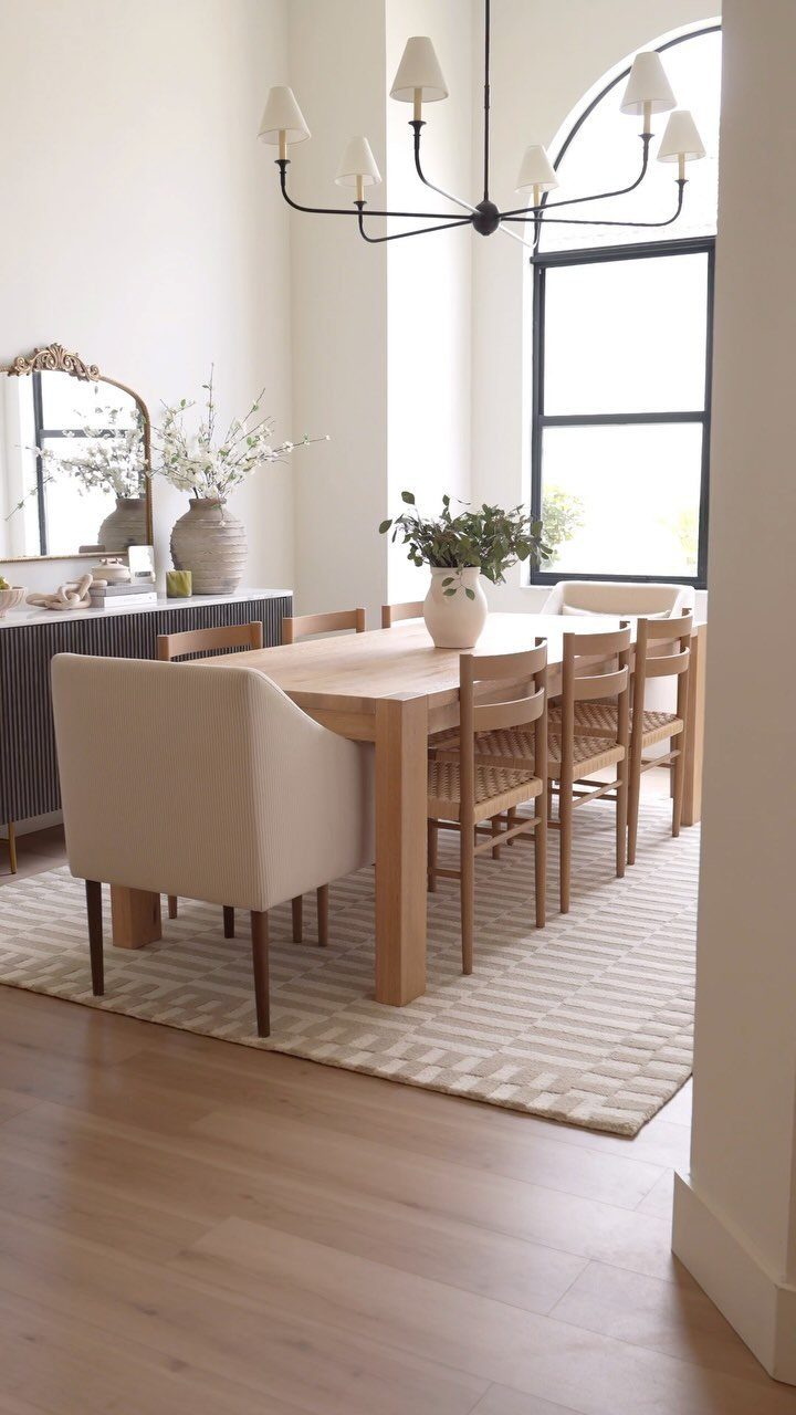 Wooden dining table and chairs on a textured cream area rug in bright room