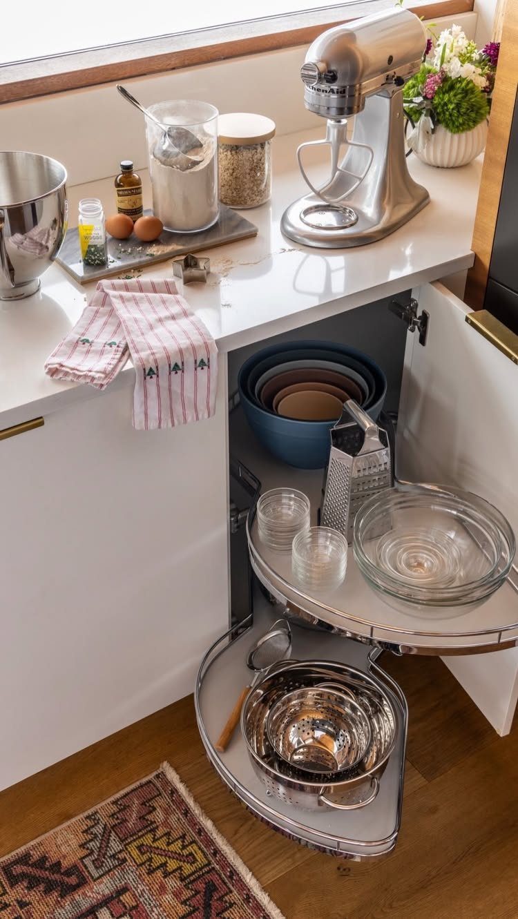 Rotating Lazy Susan shelves in a white kitchen cabinet holding various mixing bowls.