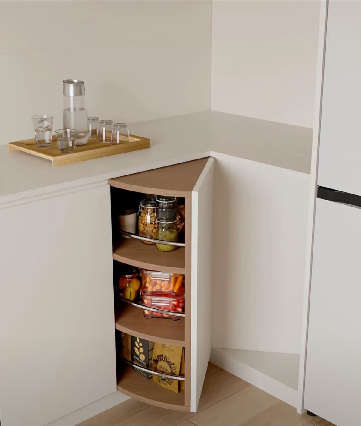 Triangular corner base cabinet with curved shelves holding jars and food containers.
