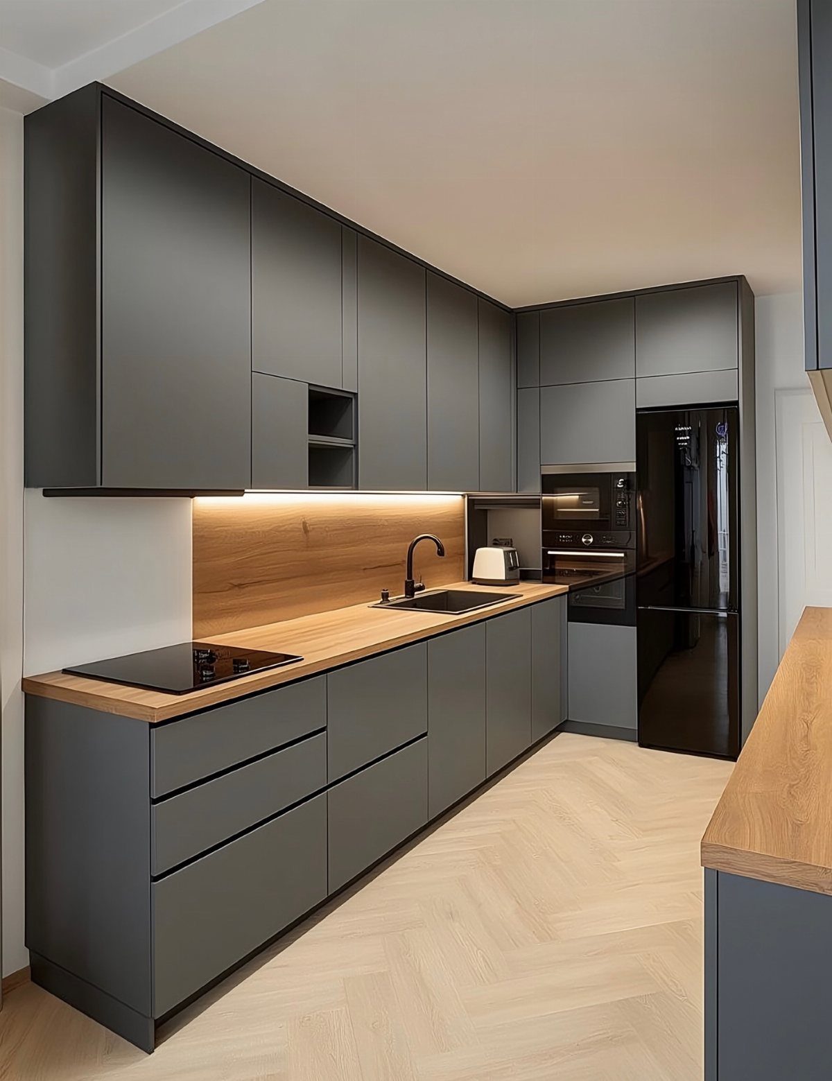Matte dark grey kitchen cabinets with light wood countertops and herringbone wood floors.