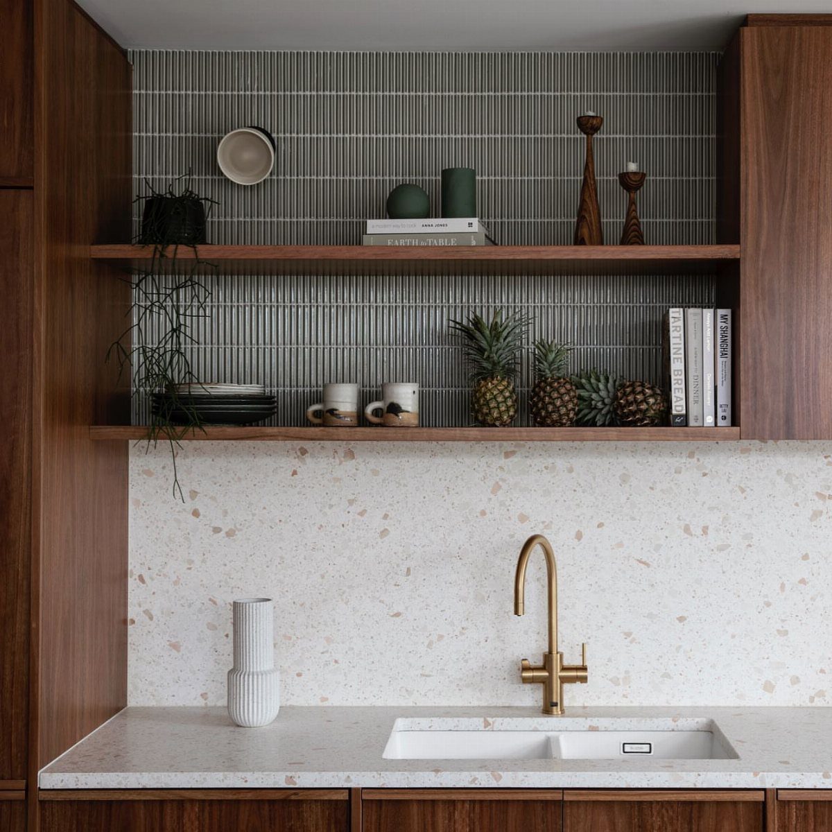 Dark wood kitchen cabinets with floating open shelves and a gold faucet.