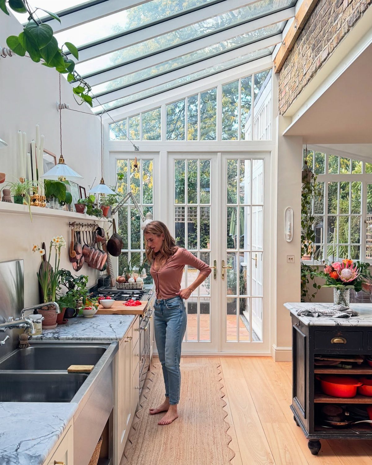 Bright kitchen with white cabinets, glass walls, and a dark kitchen island.