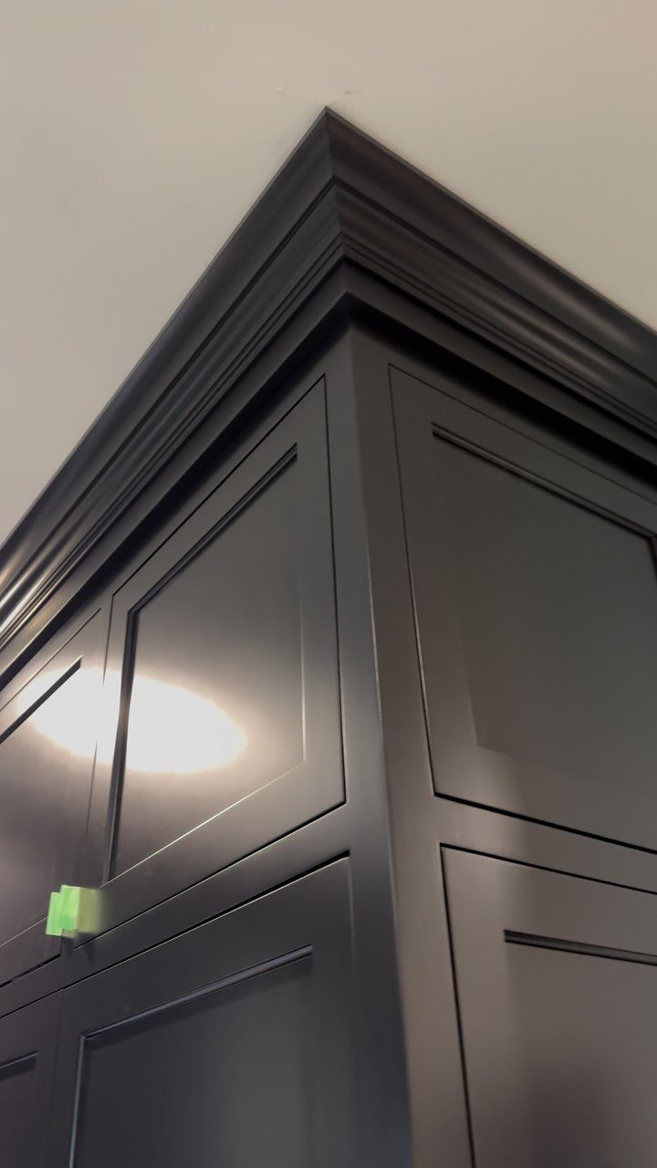 Dark grey kitchen cabinets with decorative crown molding meeting a white ceiling.