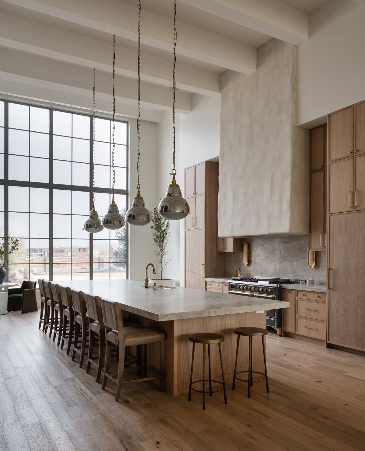 Modern kitchen with high ceilings, large windows, and a long wooden island.