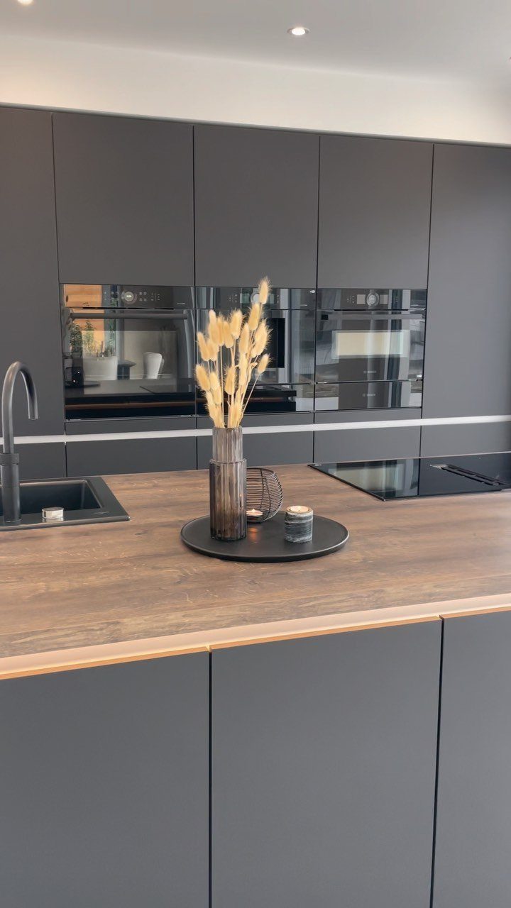 Modern grey kitchen with a wooden countertop and minimal decorative accessories on a tray.