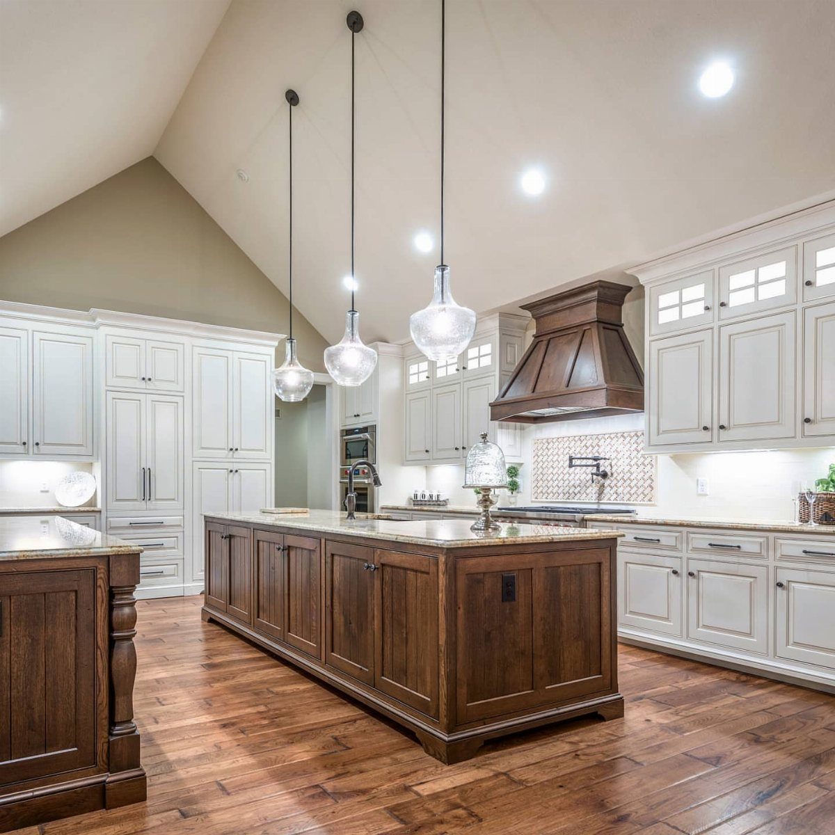 Vaulted ceiling in a kitchen with white cabinets and a large wooden island.
