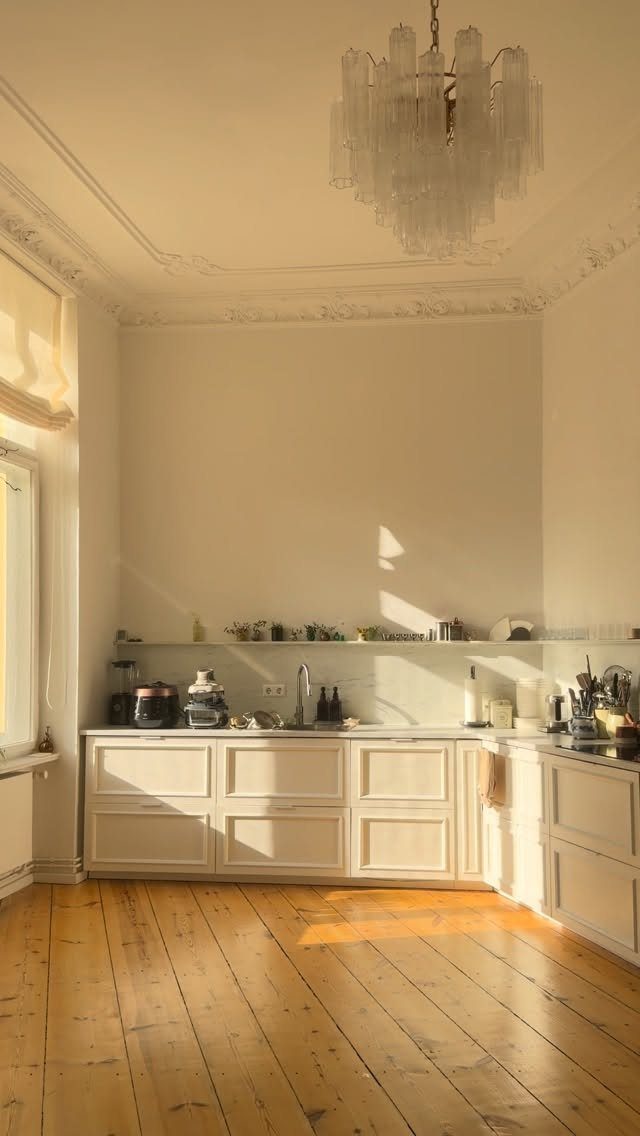 White kitchen with lower cabinets and no upper cabinets under a crystal chandelier.