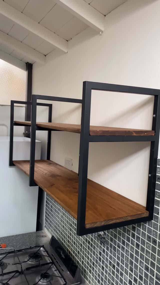 Wooden shelves with black metal frames mounted on a white kitchen wall.