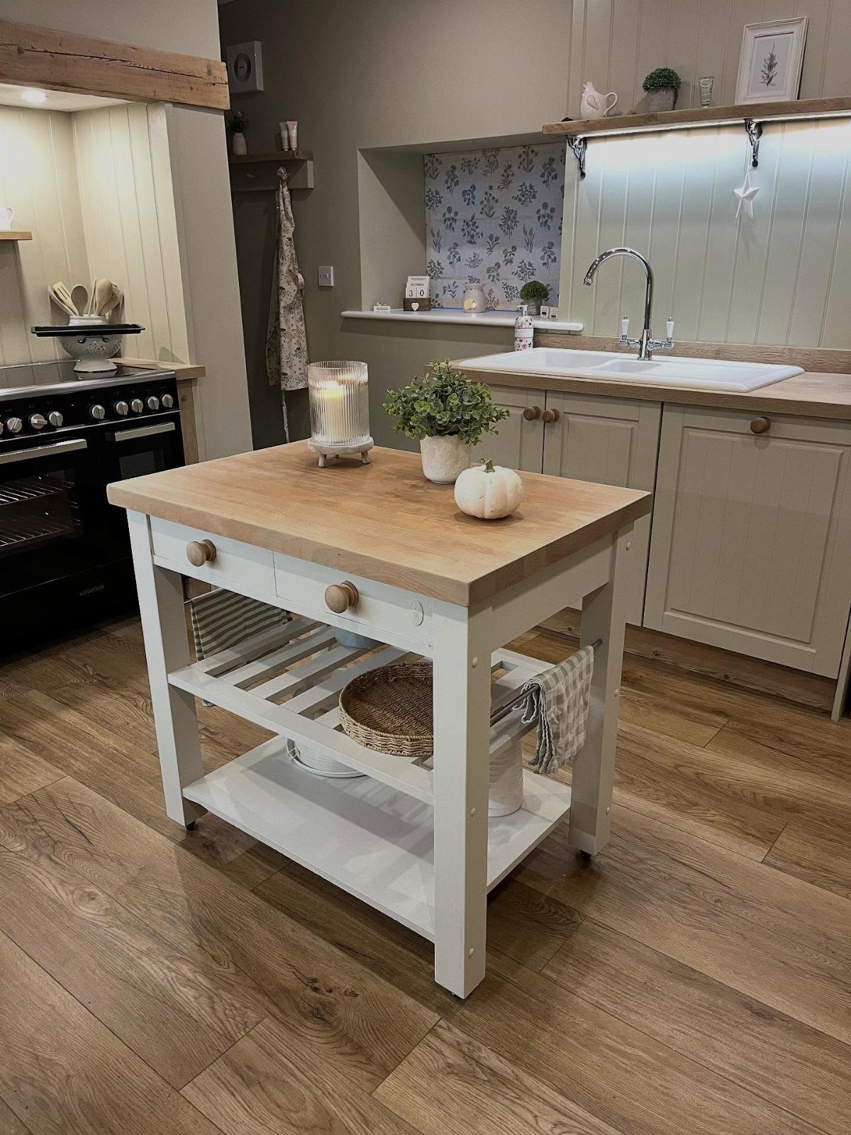Small white kitchen island with a light wood butcher block countertop and open shelving.