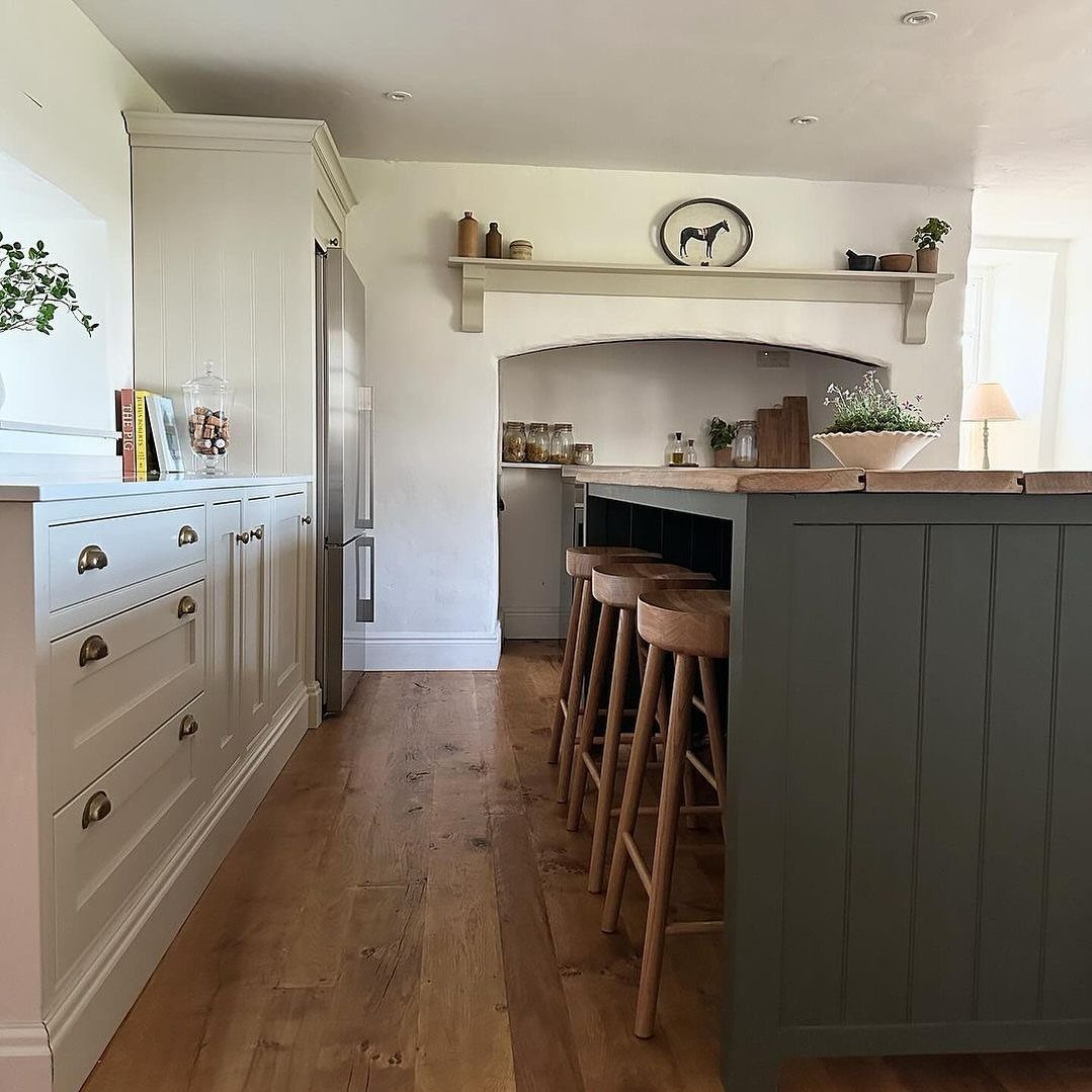 Dark green small kitchen island with wooden countertop and three matching wooden stools.