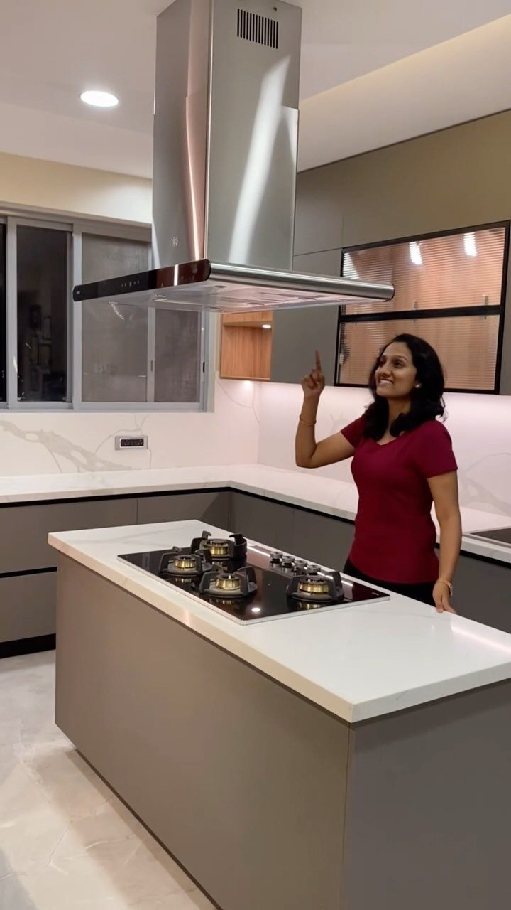 Grey kitchen island with white countertop and built-in gas cooktop and vent hood