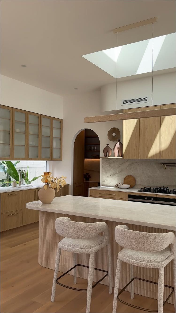 White marble kitchen island and matching perimeter counters with light wood cabinetry