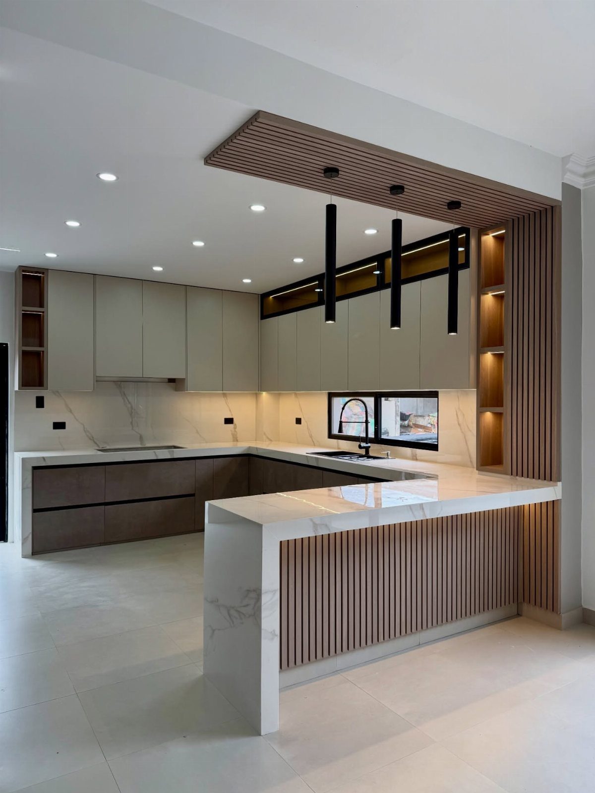 Modern kitchen with white quartz countertops and black pendant lighting over a wooden island.