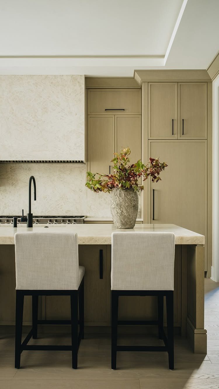 White quartz kitchen island with beige bar stools and neutral toned cabinetry.