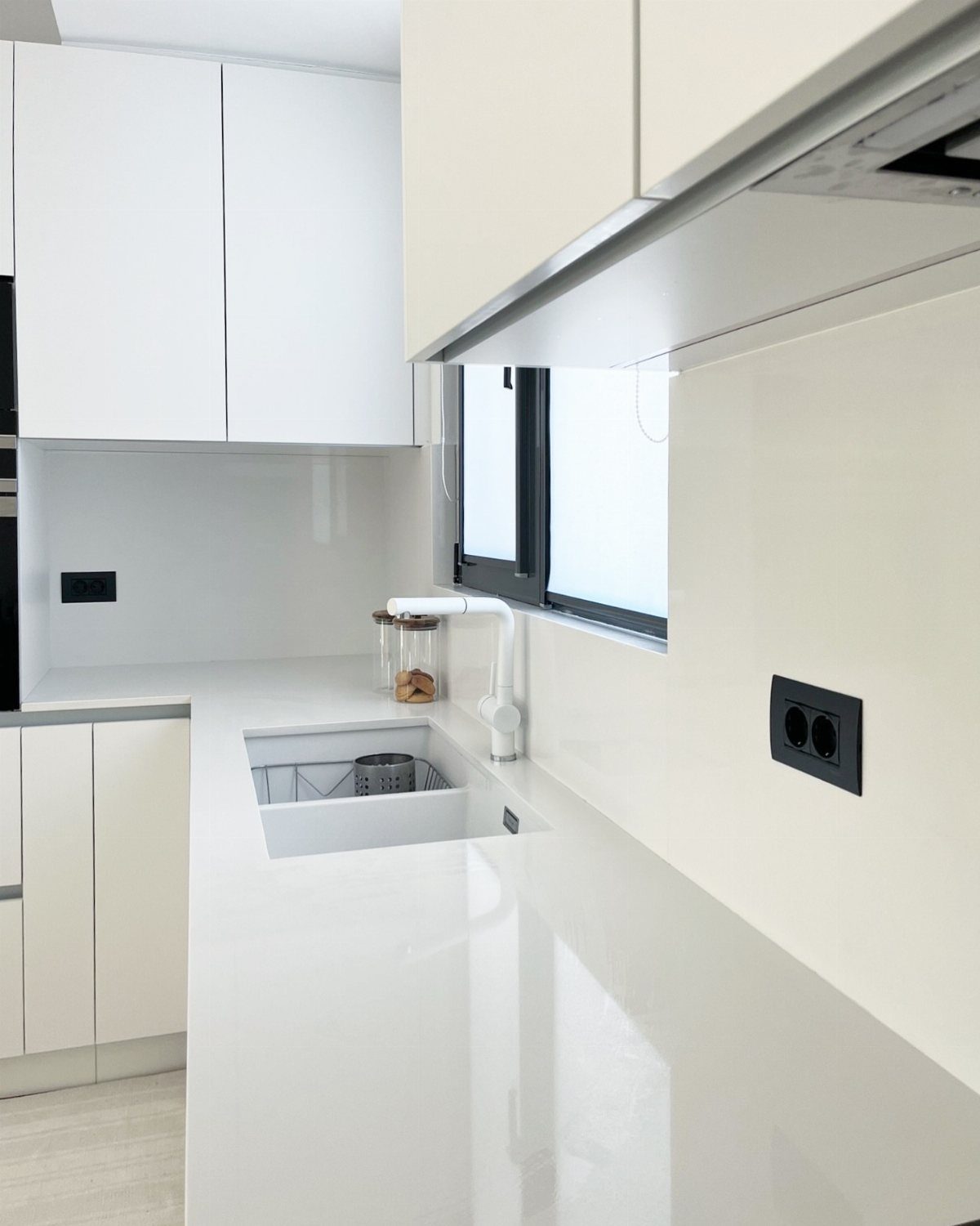 White quartz countertops in a modern kitchen with white cabinets and backsplash.