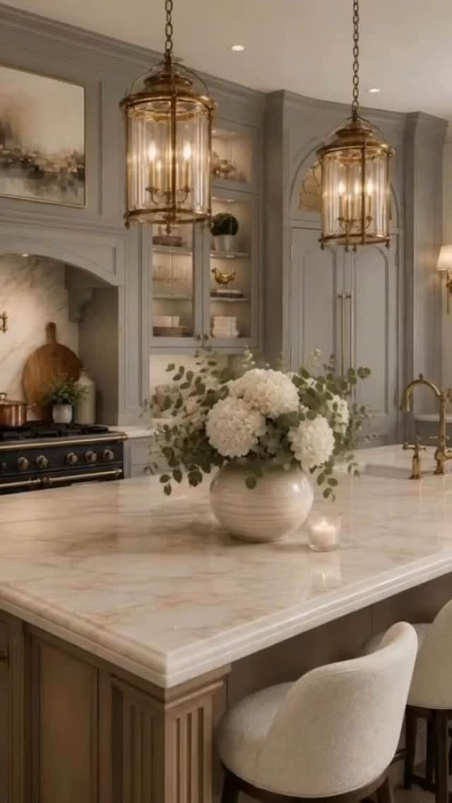 Luxury kitchen with grey cabinets, marble island, and brass lantern pendant lights.