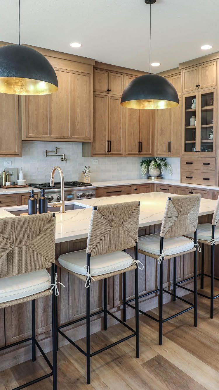 Modern kitchen with light stained wood cabinets, white marble island, and woven bar stools.