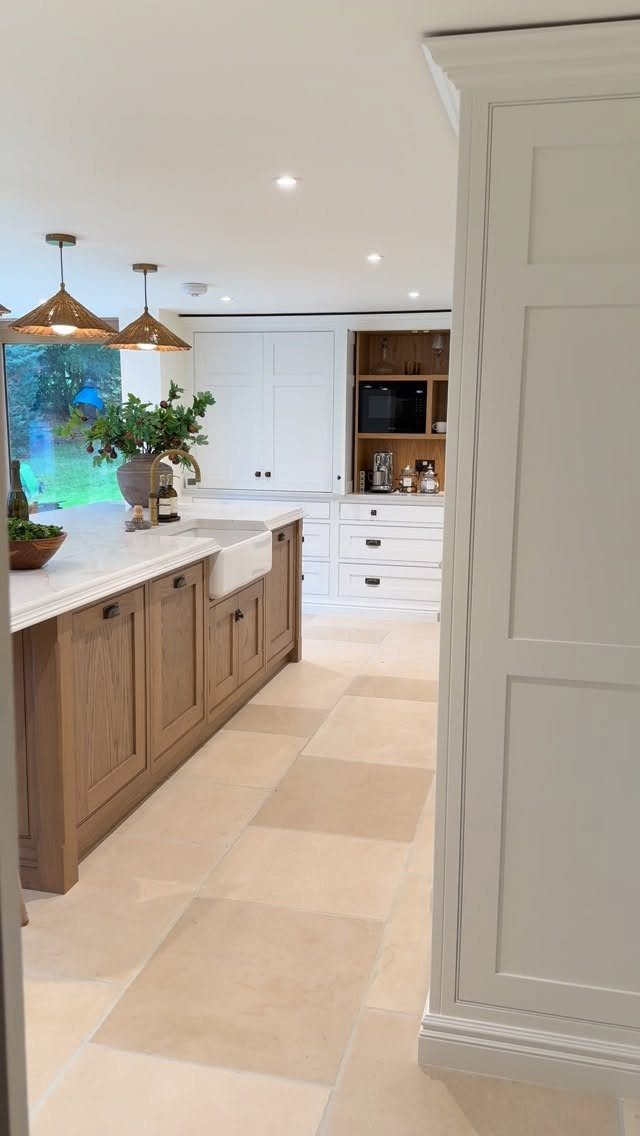 Light wood kitchen island and white cabinets with a dark wood shelving unit.