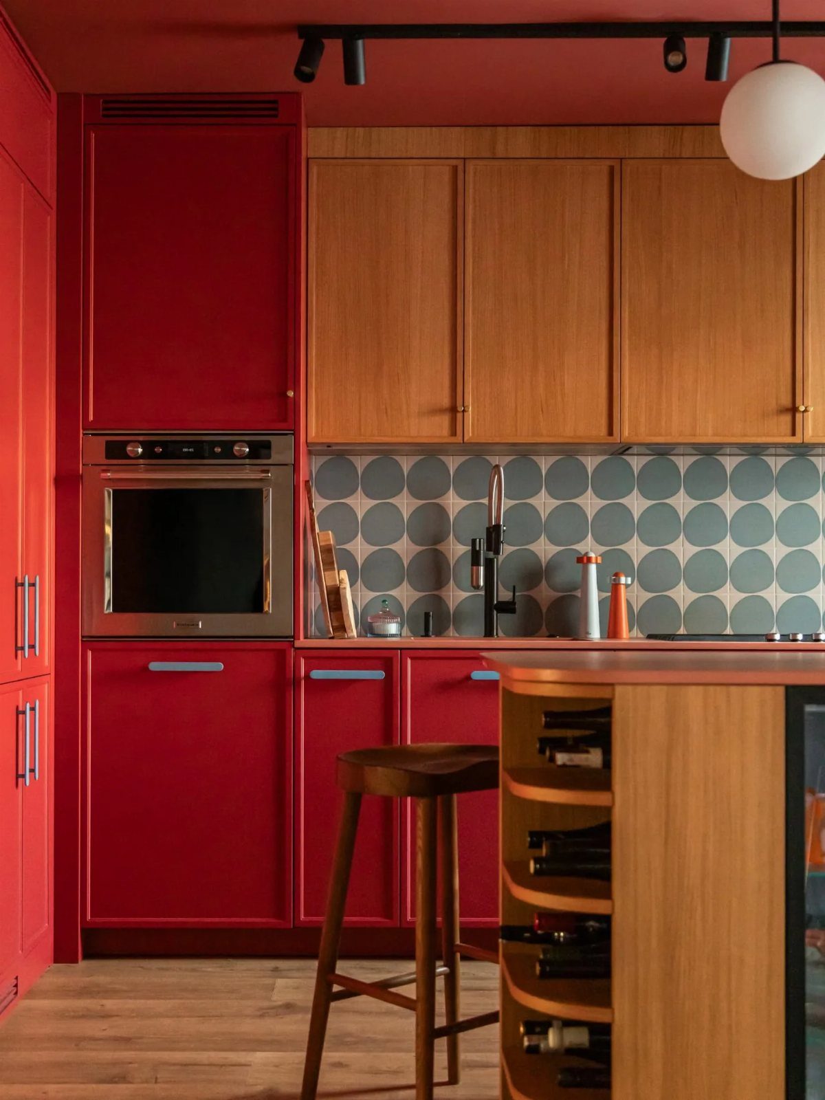 Red and walnut kitchen cabinets with a blue circular patterned tile backsplash.