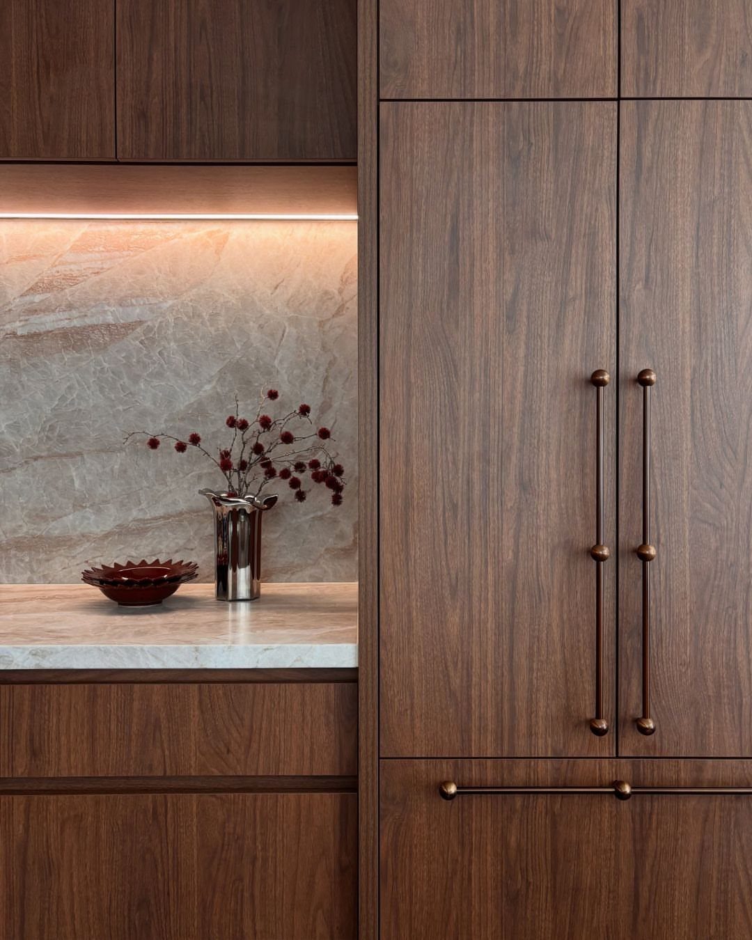 Dark walnut kitchen cabinets with white marble countertops and a matching marble backsplash.